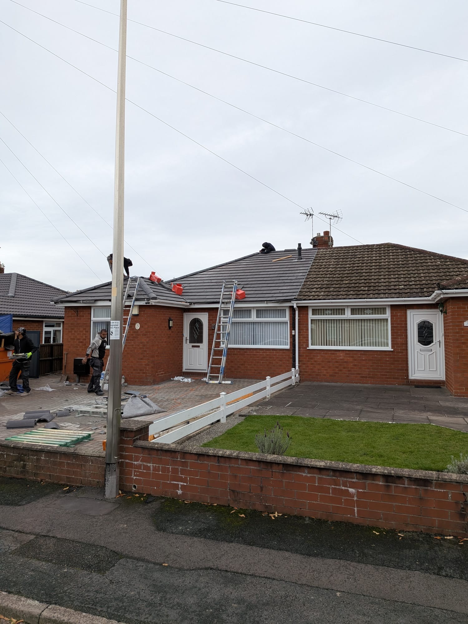 Bungalow re-roof in progress showing new tiles being laid in a Staffordshire neighbourhood