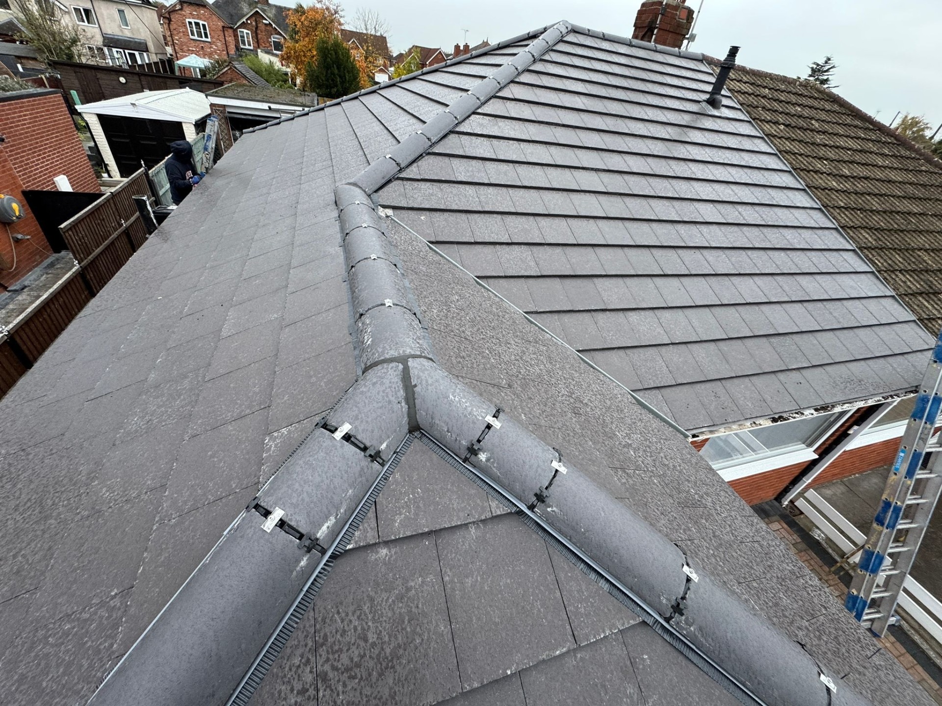 Close-up of new slate tiles and dry-fix ridge system on a completed re-roof