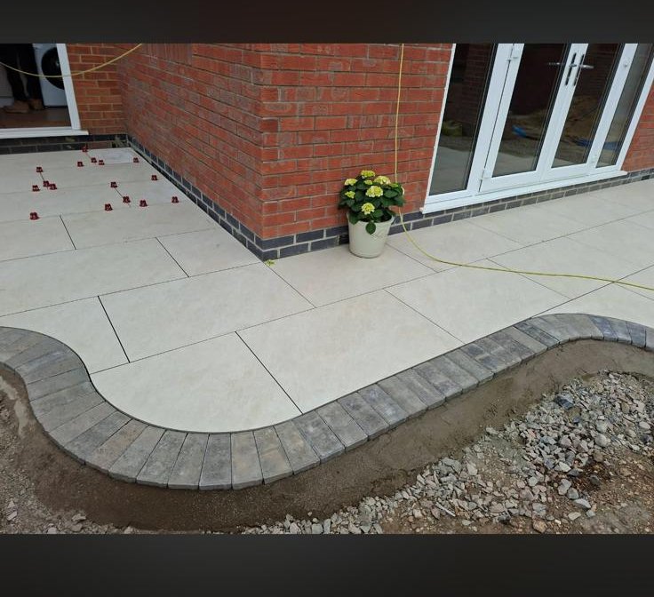 Porcelain patio under construction with curved charcoal block paving edge on a new build in Pershore