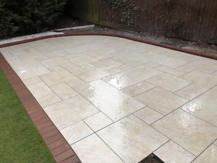 Cream porcelain patio with red brick border in a rear garden in Hereford